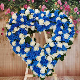 Heart-shaped floral wreath of white roses and blue chrysanthemums on an easel