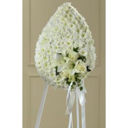 White standing floral spray with roses and lilies on a ribboned easel
