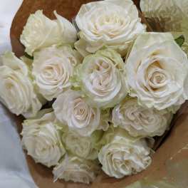 Bouquet of white roses wrapped in brown paper