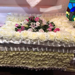 Large white floral casket spray with pink roses and lilies