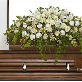White floral spray arranged on top of a wooden casket