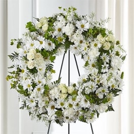White floral wreath on a black stand with daisies and roses