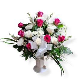 Pink and white rose arrangement in a white vase with a satin bow