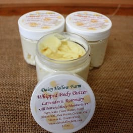 Three jars of whipped body butter on burlap, one open in front