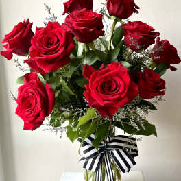 Bouquet of red roses in a clear glass vase with a striped ribbon