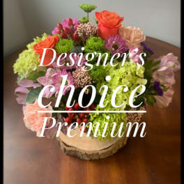 Mixed bouquet in a wood slice base with pink, orange, and green blooms