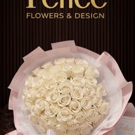 Bouquet of white roses wrapped in pale pink paper with a ribbon