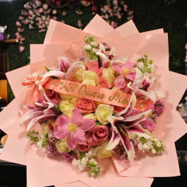 Pink bouquet with roses and lilies wrapped in pastel paper