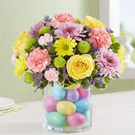 Colorful bouquet in a clear vase filled with pastel eggs