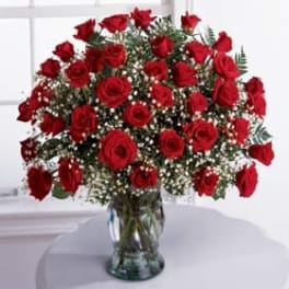 Large bouquet of long-stemmed red roses with baby's breath in a clear glass vase