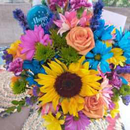Colorful bouquet with sunflowers, roses, and daisies in a vase