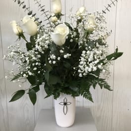 White roses and baby's breath arranged in a white vase.