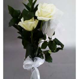 Three white roses in a clear glass vase with a white ribbon