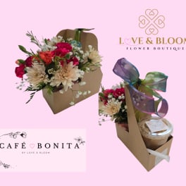 Kraft caddy holding pink and cream flowers beside an iced coffee cup with a multicolor ribbon bow.