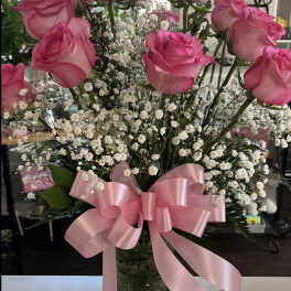 Pink roses with baby's breath in a glass vase and pink ribbon