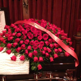 Large bouquet of red roses with a pink ribbon draped across it