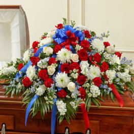 Large red, white, and blue floral casket spray with ribbons