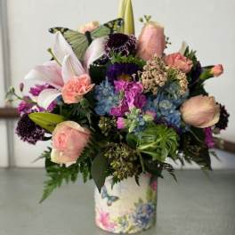 Mixed bouquet with lilies, roses, hydrangeas, and a butterfly accent in a floral vase