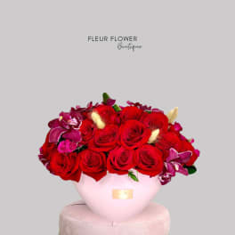 Red roses and purple orchids arranged in a pink vase