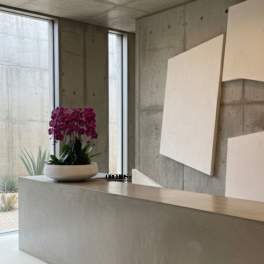 Purple orchid arrangement in a white bowl on a concrete counter