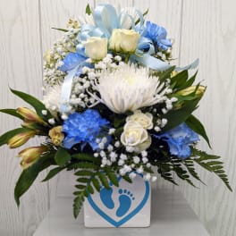 Blue and white floral arrangement in a square vase with ribbon