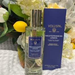 Room spray bottle and box in front of white flowers and lemons