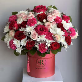 Pink and cream rose arrangement with white mums in a red hatbox-style container