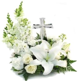 White floral arrangement with lilies, roses, and a silver cross