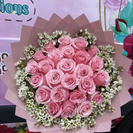 Bouquet of pink roses with small white filler flowers wrapped in pink paper