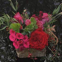 Pink and red roses arranged in a rustic wooden container