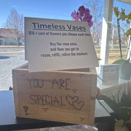 Store display sign for reusable vases with orchids in the background