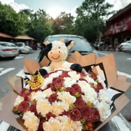 Bouquet of red and white carnations with a plush cow topper