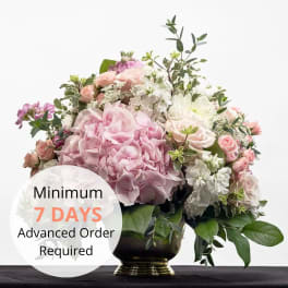Pastel pink and white hydrangea and rose arrangement in a gold pedestal vase