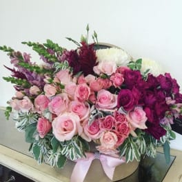 Pink and purple rose bouquet in a round box with a ribbon