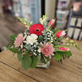 Mixed pink and white flowers arranged in a clear glass vase