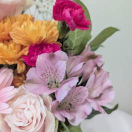 Bouquet of pink, peach, and magenta flowers with green leaves