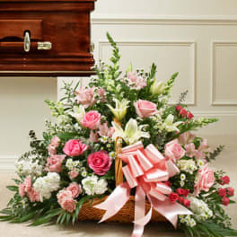 Large pink and white floral spray in a wicker basket with a pink ribbon