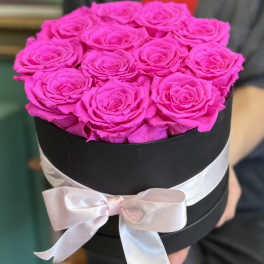 Bright pink roses arranged in a black round box with a pale ribbon bow
