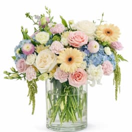 Pastel mixed bouquet in a clear glass vase with roses, gerbera daisies, and carnations