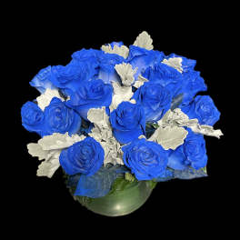 Blue roses arranged in a round vase with silver foliage