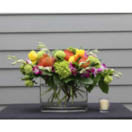 Mixed bouquet in a clear glass vase with a small candle beside it