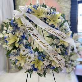 Floral wreath with white and blue flowers and yellow lilies on an easel