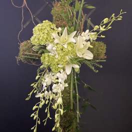 Cross-shaped floral arrangement with white lilies, green hydrangeas, and orchids