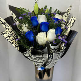 Bouquet of blue and white roses in a tall metallic vase