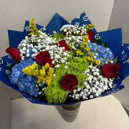 Bouquet of red roses, blue hydrangeas, and white baby's breath in blue wrap