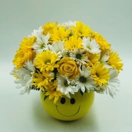 Yellow and white flowers arranged in a smiley-face pot