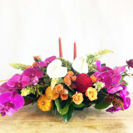 Low floral centerpiece with orchids, roses, and candles