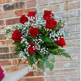 Bouquet of red roses and white baby's breath in a clear glass vase