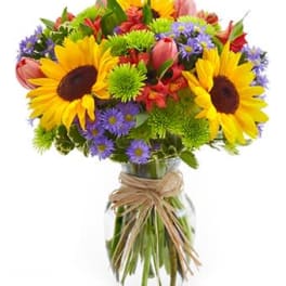 Bouquet of sunflowers, purple daisies, and pink tulips in a glass vase