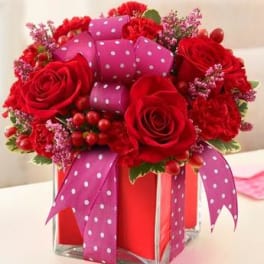 Red roses and pink ribbon in a square glass vase